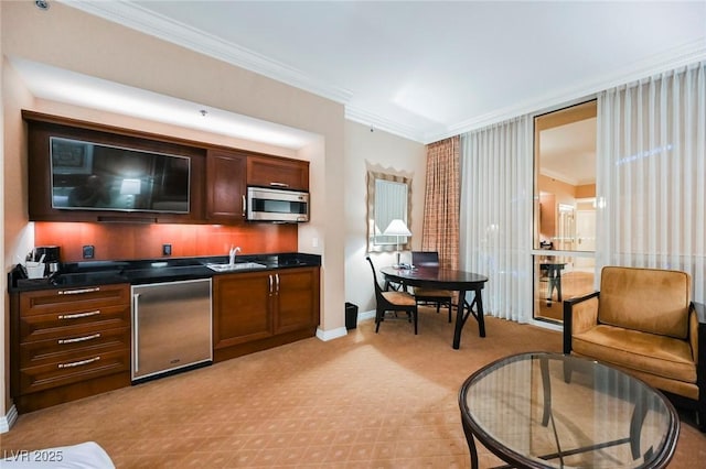 kitchen with dark countertops, stainless steel microwave, ornamental molding, fridge, and a sink