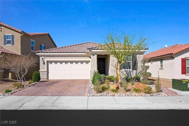 view of front of home featuring decorative driveway, a tiled roof, an attached garage, and stucco siding