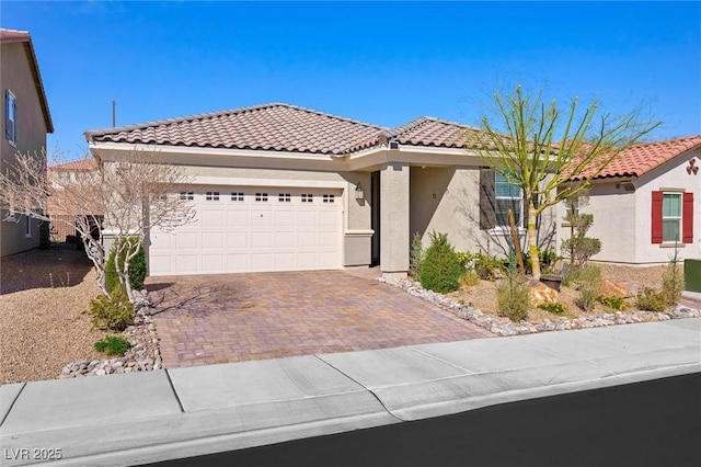 view of front facade featuring decorative driveway, a tiled roof, an attached garage, and stucco siding