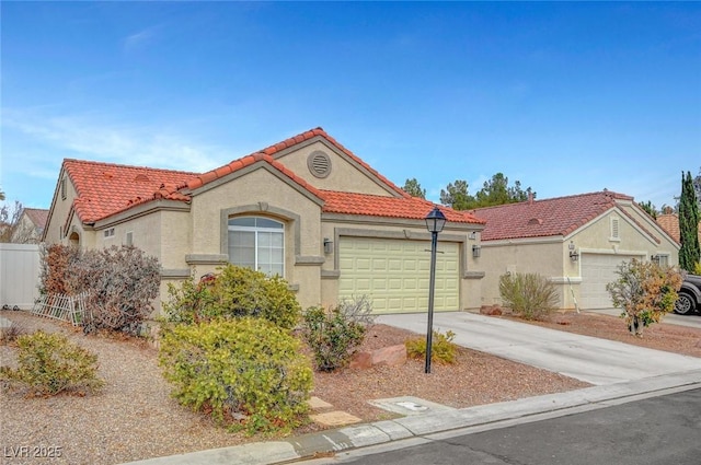 mediterranean / spanish house featuring concrete driveway, a tiled roof, an attached garage, and stucco siding