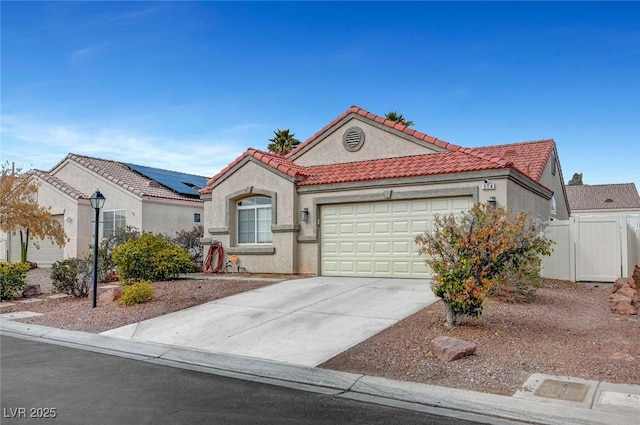 view of front of property featuring an attached garage, fence, a tiled roof, concrete driveway, and stucco siding