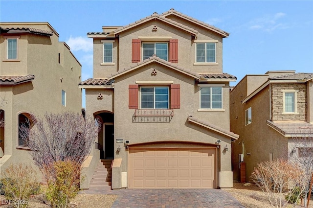 view of front of house with decorative driveway, an attached garage, a tile roof, and stucco siding