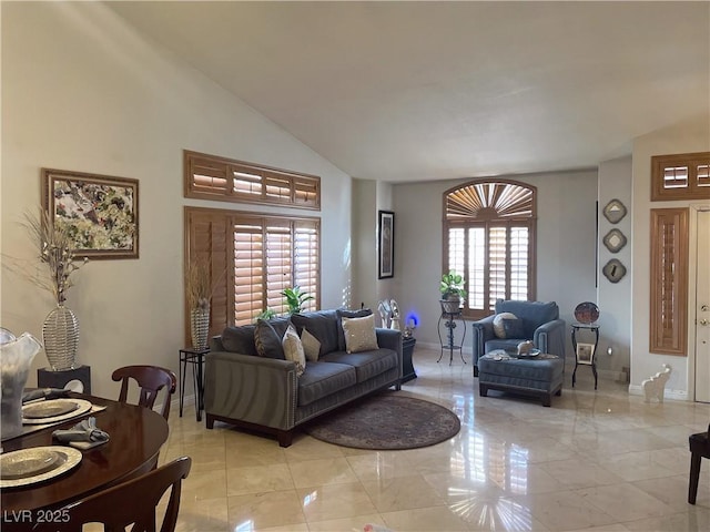 living room featuring high vaulted ceiling and baseboards