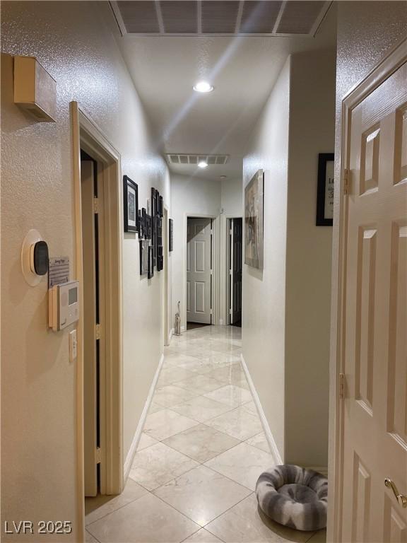 hall with visible vents, baseboards, and light tile patterned floors