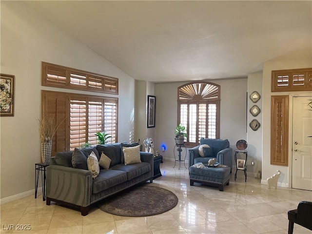 living area featuring vaulted ceiling and baseboards