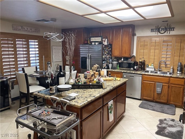 kitchen with appliances with stainless steel finishes, brown cabinetry, visible vents, and a sink