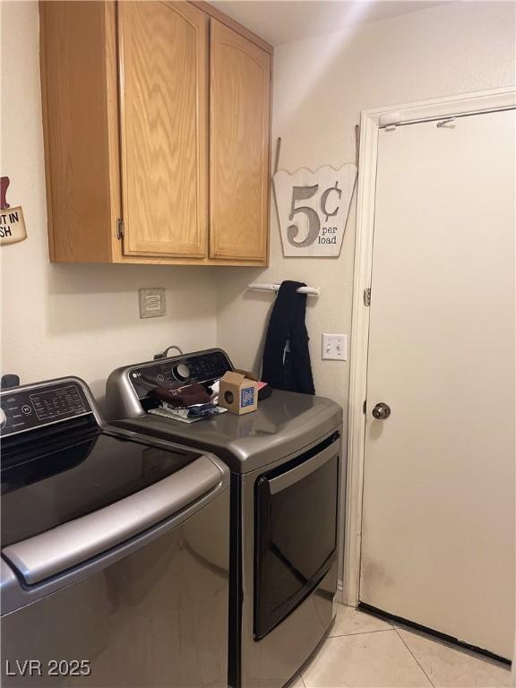 washroom featuring cabinet space, washing machine and clothes dryer, and light tile patterned floors