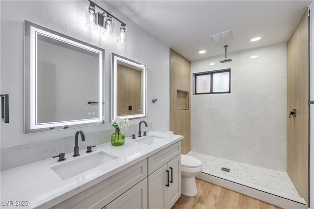 bathroom with a tile shower, wood finished floors, and a sink