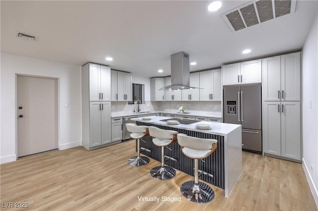 kitchen with visible vents, island exhaust hood, appliances with stainless steel finishes, and a breakfast bar