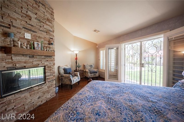 bedroom featuring wood finish floors, a fireplace, visible vents, vaulted ceiling, and access to outside