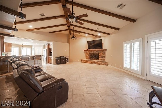 living area with a stone fireplace, beamed ceiling, visible vents, and baseboards