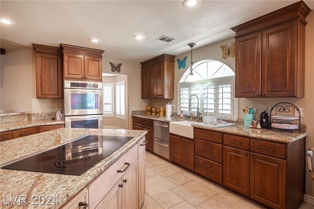 kitchen with a sink, light stone countertops, black electric cooktop, double oven, and a wealth of natural light