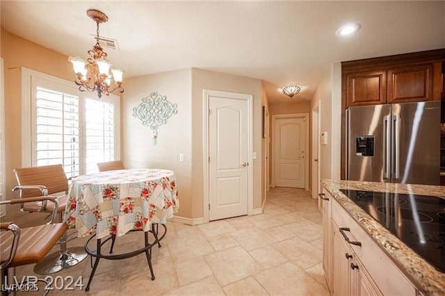 kitchen featuring black electric cooktop, baseboards, hanging light fixtures, stainless steel refrigerator with ice dispenser, and light stone countertops