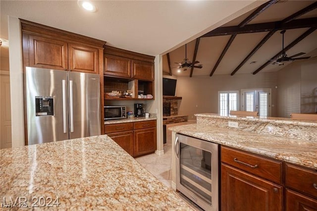 kitchen with beverage cooler, stainless steel appliances, a ceiling fan, and brown cabinets