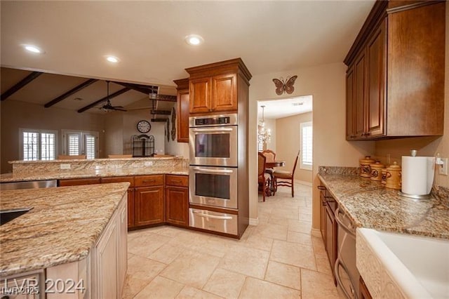 kitchen with stainless steel appliances, light stone counters, and brown cabinetry