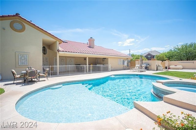 view of swimming pool with a pool with connected hot tub, fence, and a patio