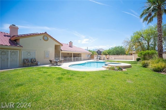 view of swimming pool featuring a patio area, a pool with connected hot tub, fence, and a yard