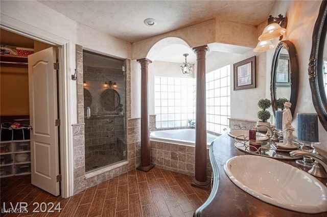 bathroom with a stall shower, a spacious closet, wood finish floors, ornate columns, and a sink