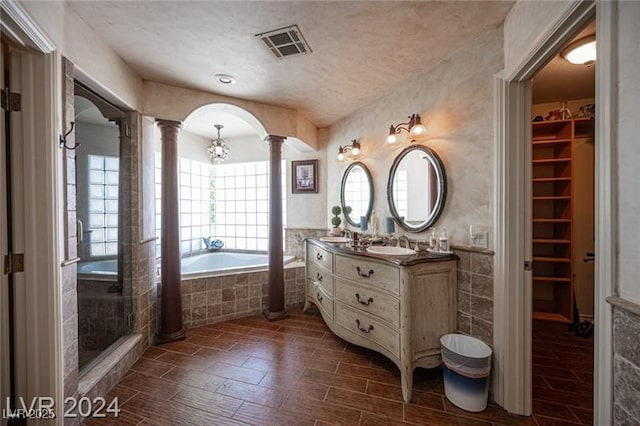 bathroom with visible vents, wood tiled floor, a walk in closet, ornate columns, and a bath