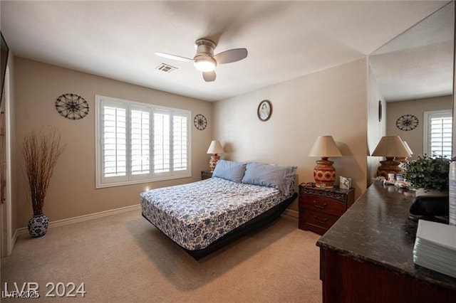 bedroom with light carpet, ceiling fan, visible vents, and baseboards