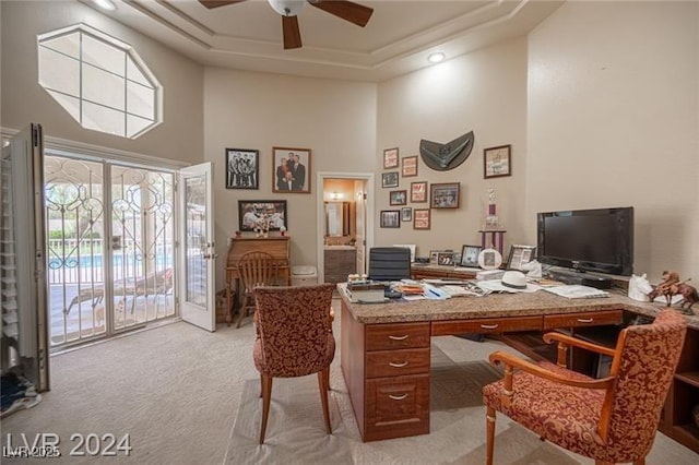 office space with light colored carpet, a high ceiling, a ceiling fan, french doors, and a raised ceiling