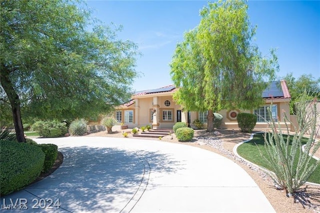 mediterranean / spanish house with concrete driveway, solar panels, and stucco siding