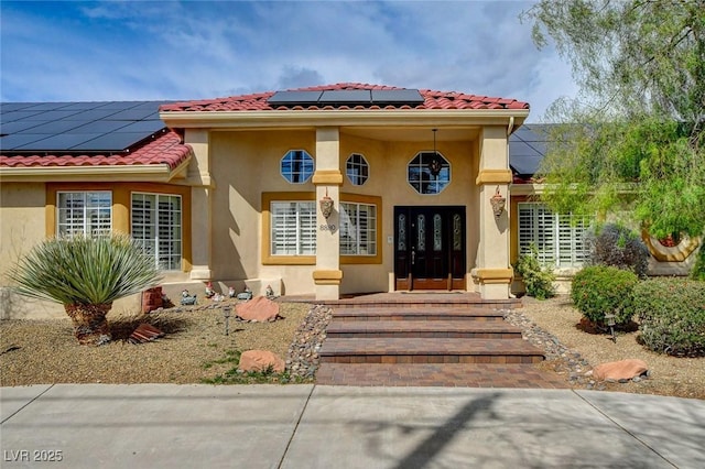 property entrance featuring stucco siding, roof mounted solar panels, and a tile roof