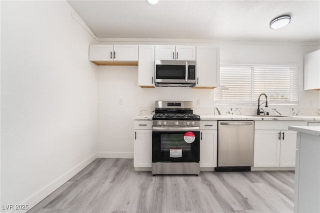 kitchen with baseboards, stainless steel appliances, light countertops, and white cabinets