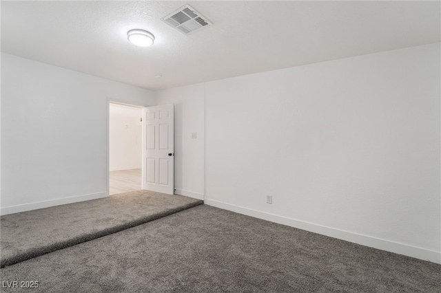 empty room with a textured ceiling, carpet flooring, visible vents, and baseboards