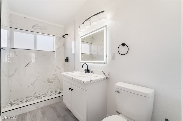 full bath featuring toilet, a marble finish shower, wood finished floors, and vanity