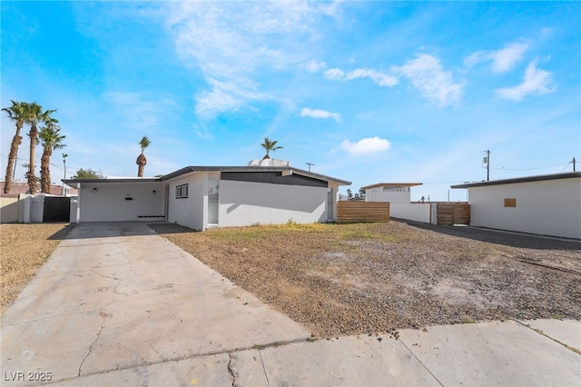 view of front facade with concrete driveway and fence