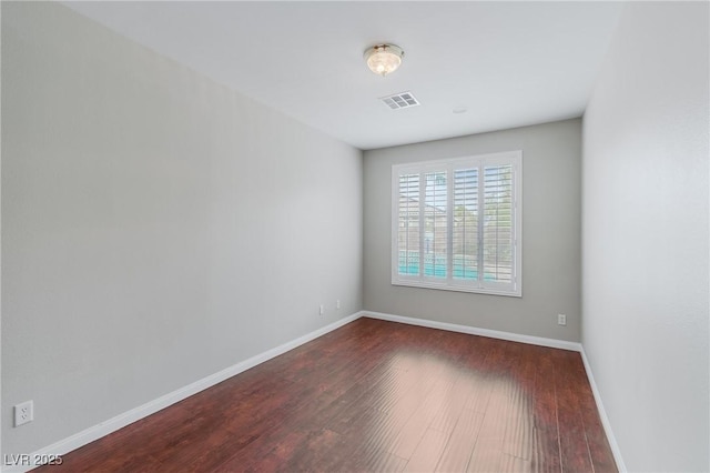 empty room featuring baseboards, visible vents, and dark wood-type flooring