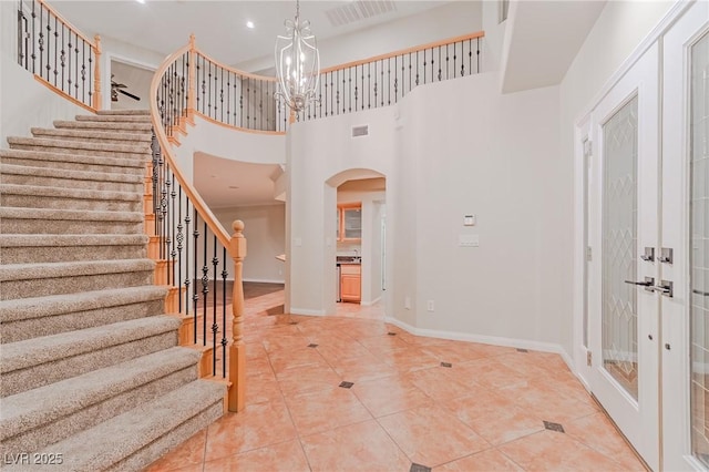 foyer featuring visible vents, arched walkways, a notable chandelier, and french doors