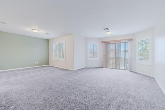 unfurnished room with carpet, visible vents, and baseboards