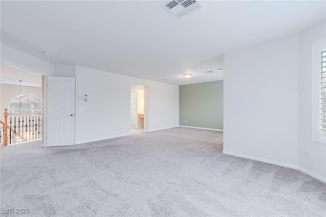 spare room with plenty of natural light, carpet, visible vents, and baseboards