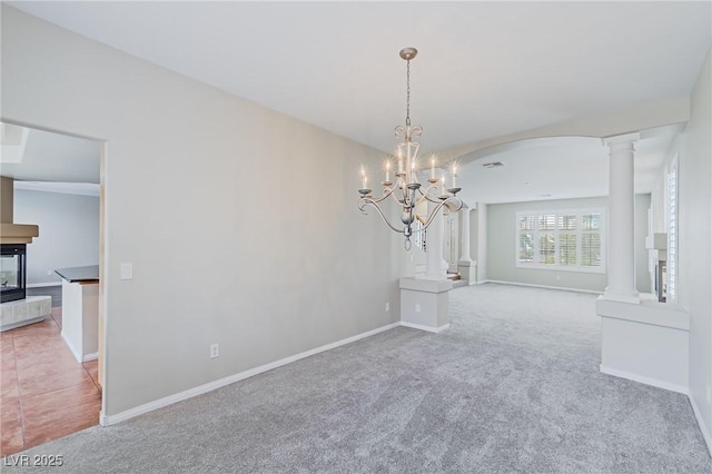 unfurnished room featuring baseboards, decorative columns, and light colored carpet