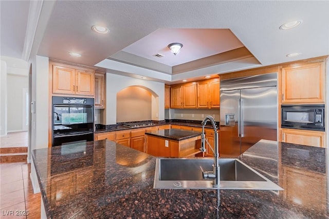 kitchen with light tile patterned floors, a kitchen island, a sink, black appliances, and a raised ceiling