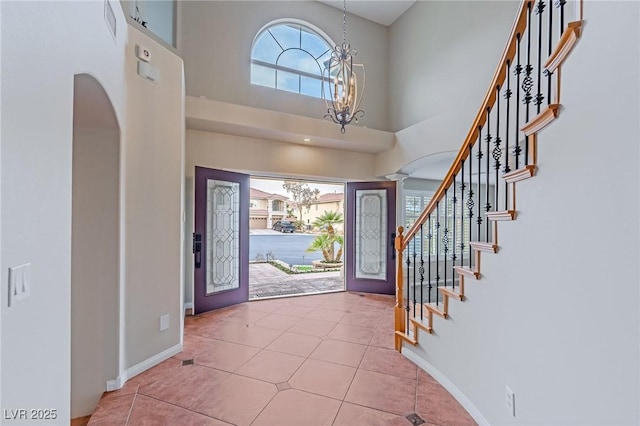 foyer with a notable chandelier, stairway, a high ceiling, baseboards, and tile patterned floors