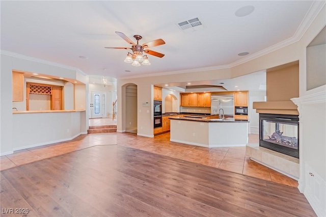 unfurnished living room with arched walkways, ornamental molding, and visible vents