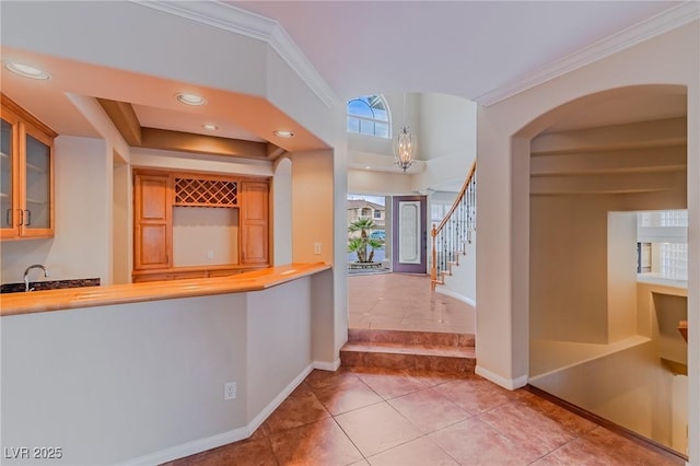 foyer entrance with baseboards, stairs, wet bar, crown molding, and recessed lighting