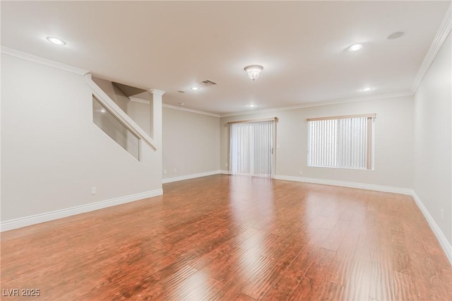 empty room with baseboards, visible vents, wood finished floors, and ornamental molding