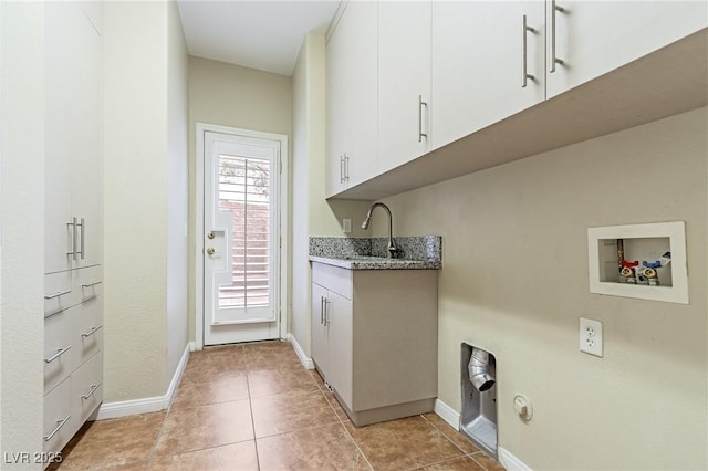 clothes washing area with hookup for a washing machine, cabinet space, baseboards, and light tile patterned floors