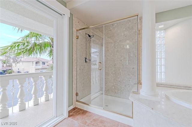 bathroom with a stall shower, tile patterned flooring, and decorative columns