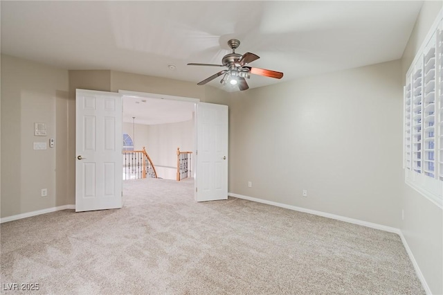 carpeted spare room with ceiling fan and baseboards