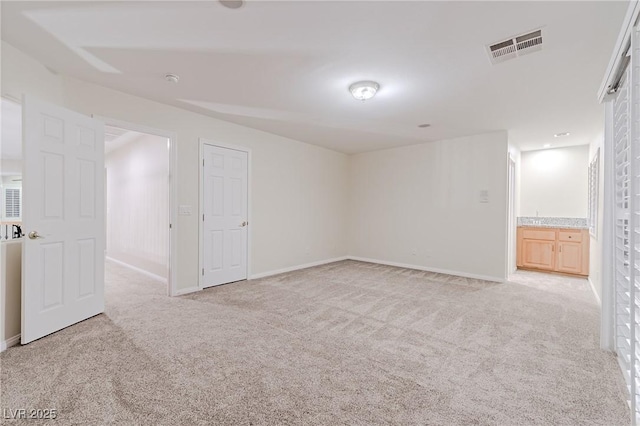 basement featuring baseboards, visible vents, and light colored carpet