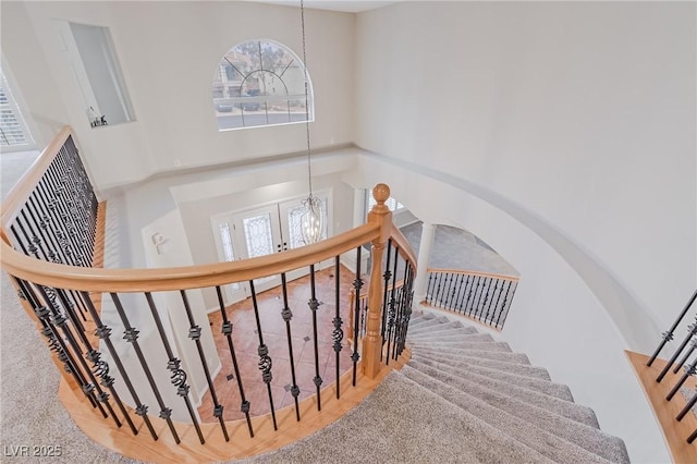 staircase with a high ceiling and a notable chandelier