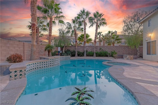 pool at dusk featuring a fenced in pool, a fenced backyard, and an in ground hot tub