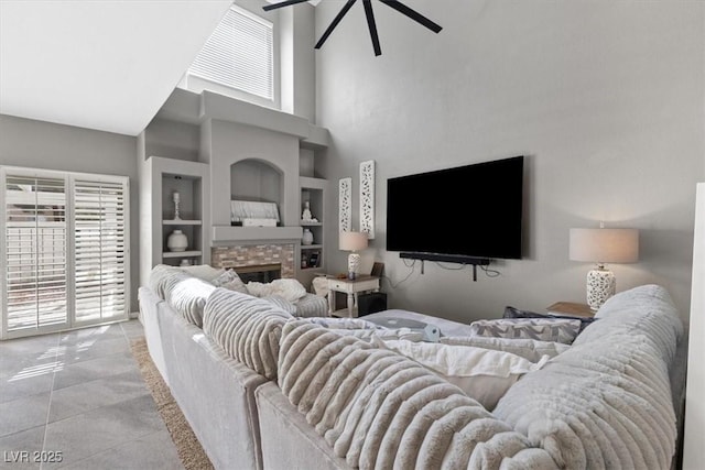 living area featuring plenty of natural light, built in shelves, a fireplace, and a ceiling fan