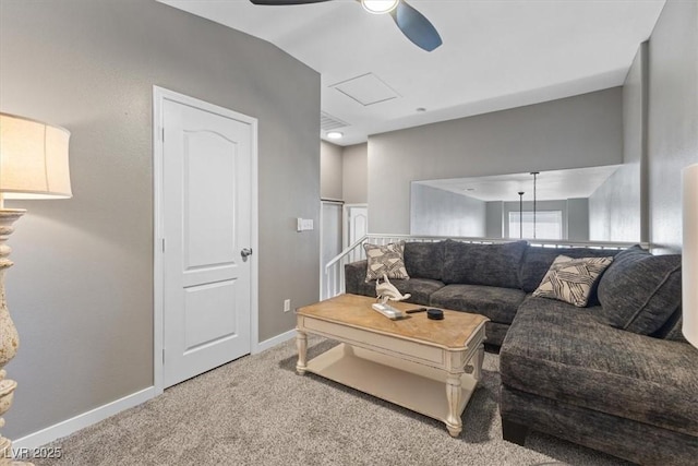 carpeted living room featuring a ceiling fan, attic access, and baseboards