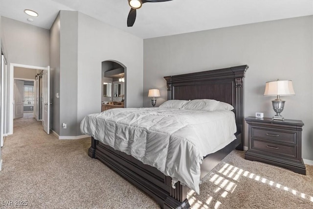 bedroom featuring baseboards, arched walkways, a ceiling fan, connected bathroom, and carpet floors